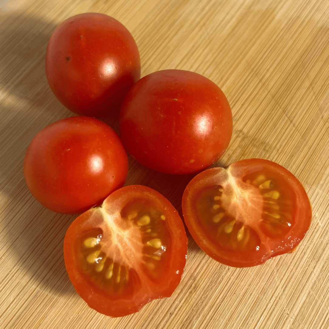Fresh Peacevine tomato from Hudson Valley Seed Co., showcasing vibrant red color and ripe, juicy appearance on the vegetable plant.
