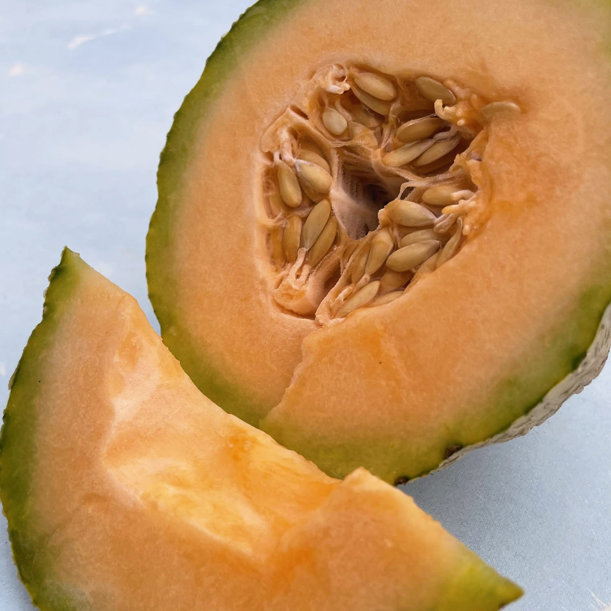 Fresh Pride of Wisconsin melon showing its bright orange flesh and green rind, a delicious vegetable variety.