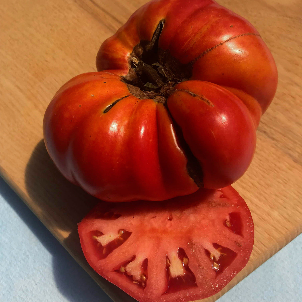 Pink Brandywine Tomato from Hudson Valley Seed Co., ripe, heirloom vegetable with large pink fruits on the vine.