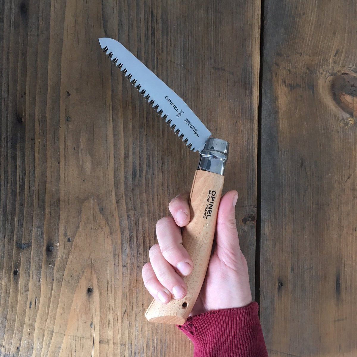 Opinel folding saw knife with wooden handle and sharp blade, ideal for camping and outdoor cutting tasks.