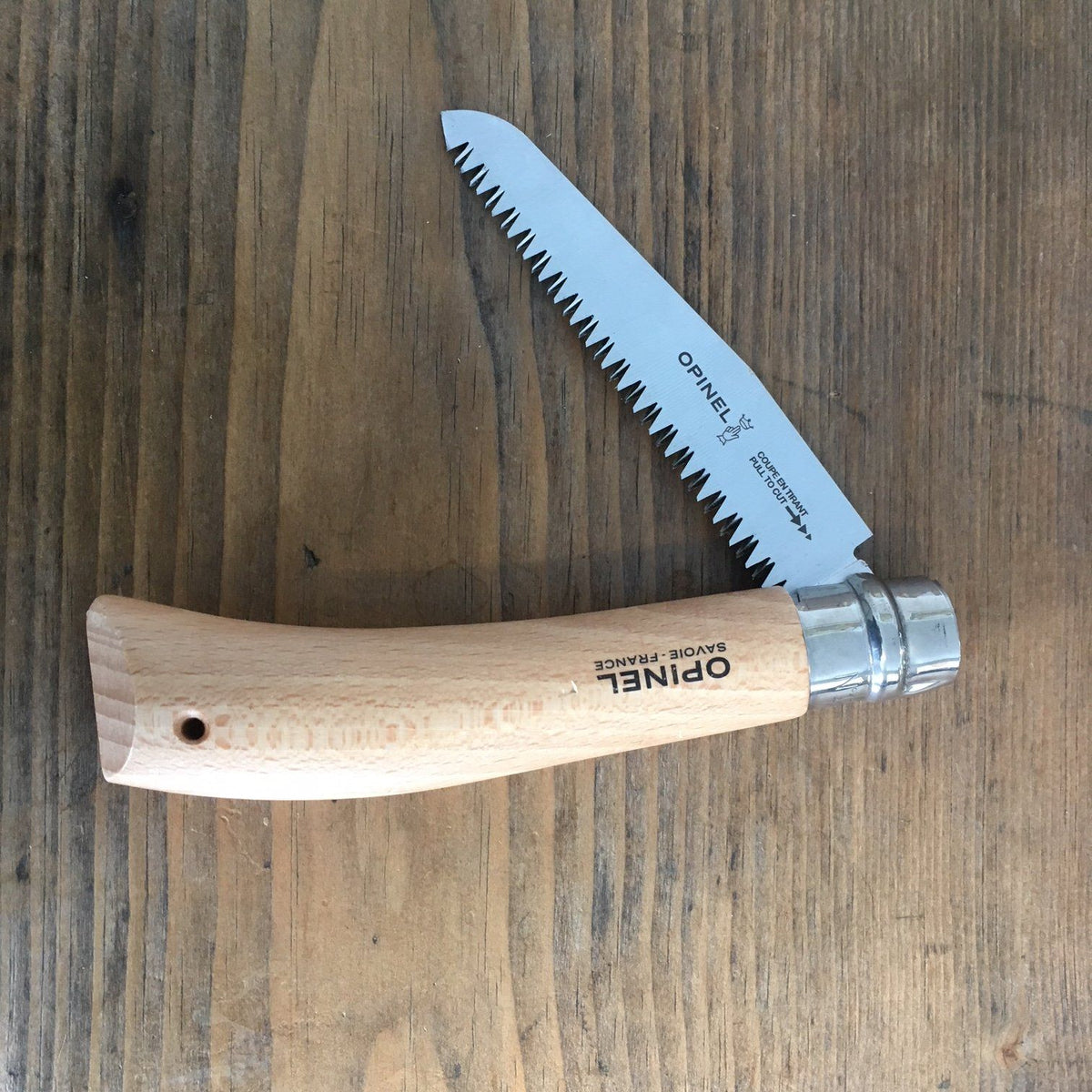 Opinel folding saw knife displayed with its wooden handle and sharp folding blade, ideal for outdoor tools and camping supplies.