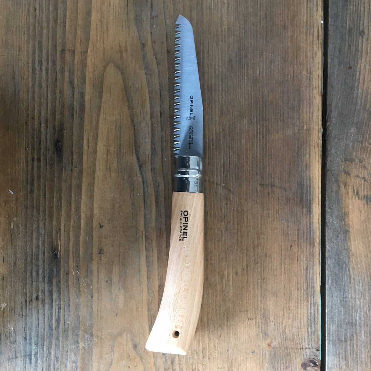 Opinel folding saw knife with wooden handle and metal blade, ideal for outdoor cutting and woodworking tasks.
