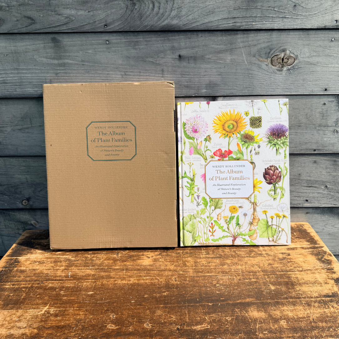Open botanical album showcasing colorful illustrations of various plant families from Botanical Arts Press LLC.
