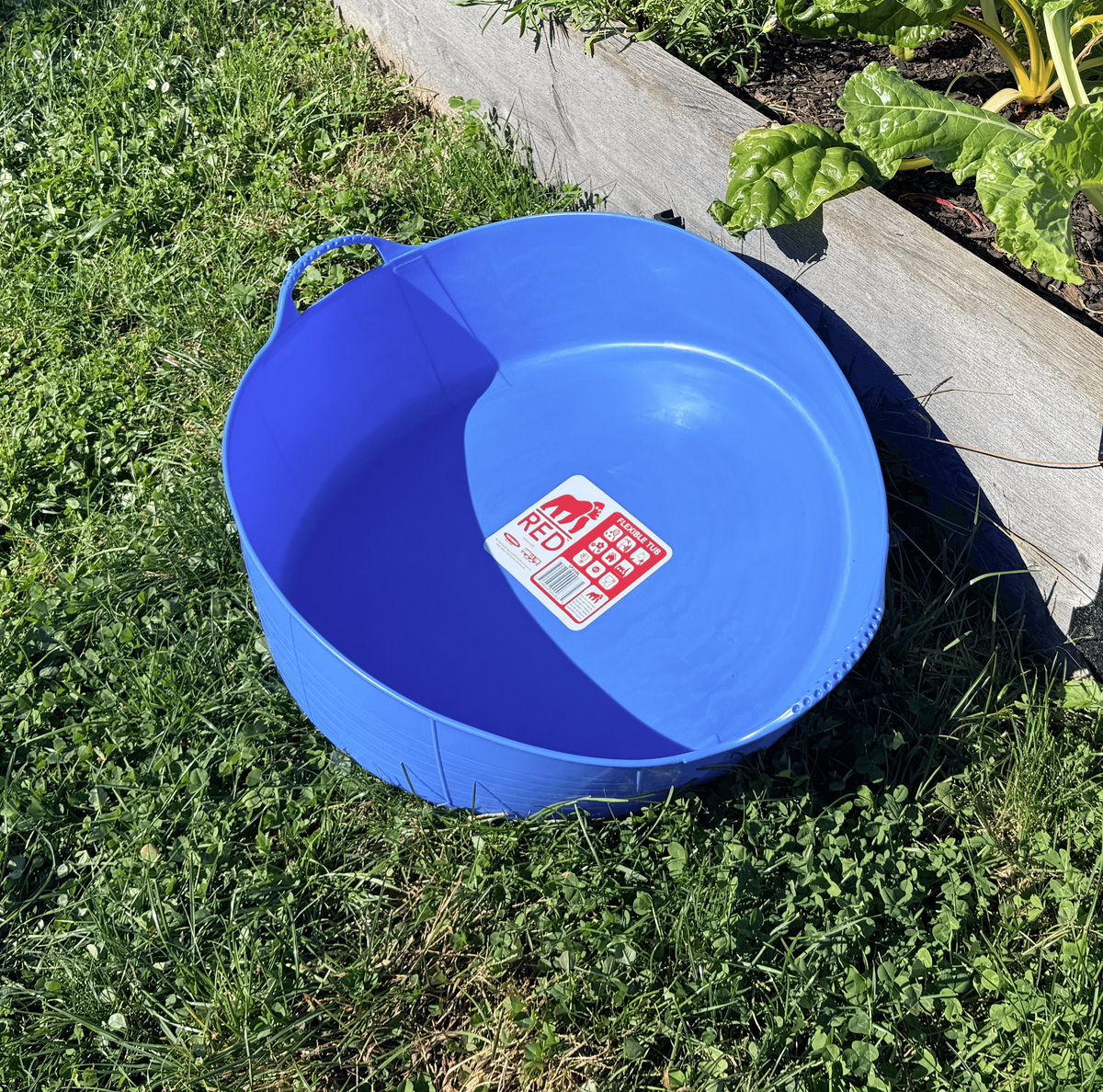 Red Gorilla 9.3-gallon shallow garden tub for planting and watering, shown on a garden surface with handles and durable plastic construction.