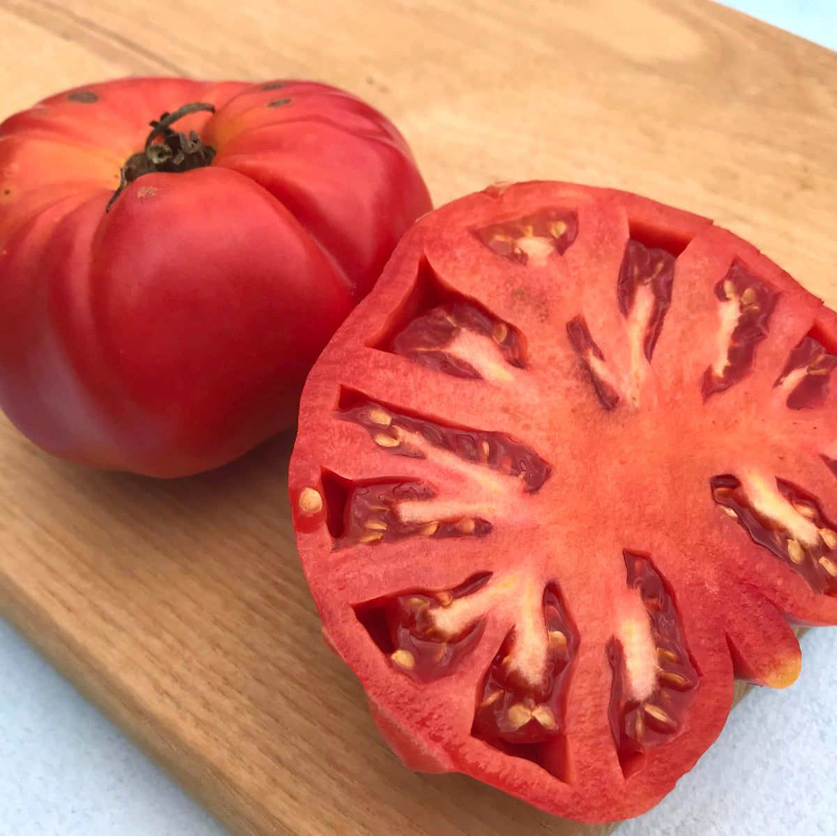 Prudens Purple Tomato from Hudson Valley Seed Co., vibrant purple heirloom vegetable with smooth skin and ripe, round shape.