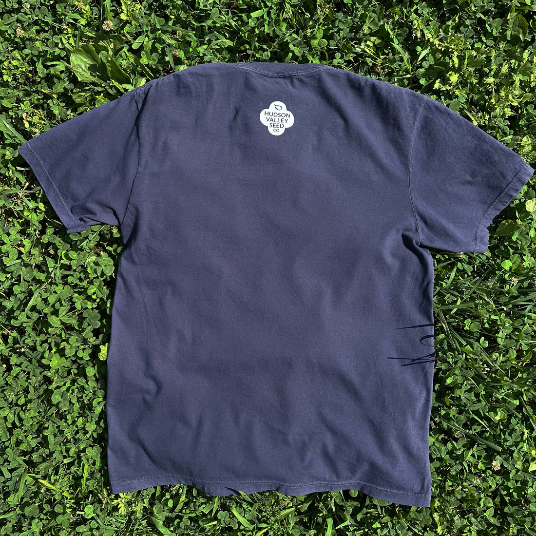 Navy Hudson Valley Seed Co logo T-shirt with a front graphic, displayed on a blue background. Casual cotton t-shirt for gardening enthusiasts.
