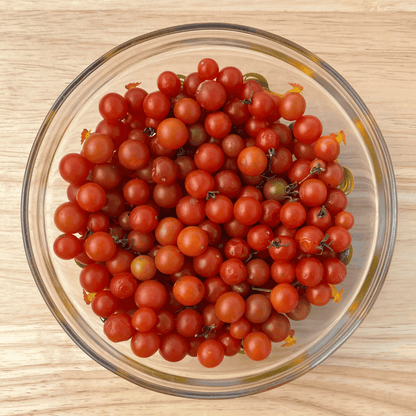 Bright red Sweet Pea Currant tomatoes, small round vegetables, fresh and ripe, shown in a close-up image.