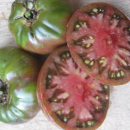 Black Krim tomato seedlings from Hudson Valley Seed Co. growing in a garden bed with lush green leaves.