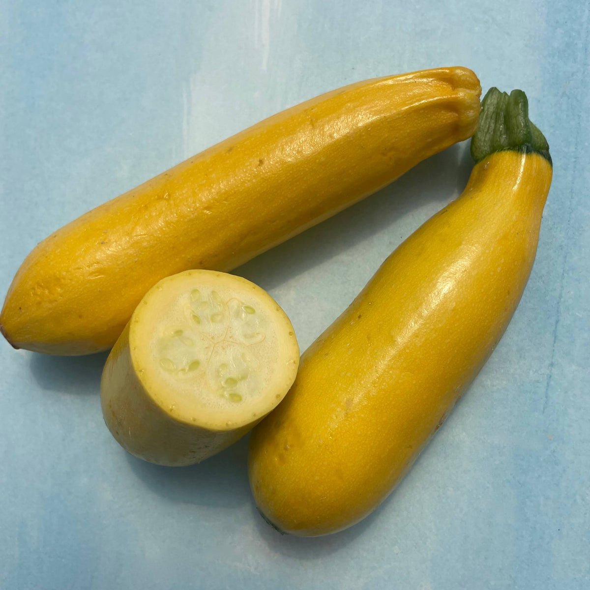 Fresh golden zucchini vegetables, vibrant yellow-green zucchinis with smooth skin, displayed on a clean surface.