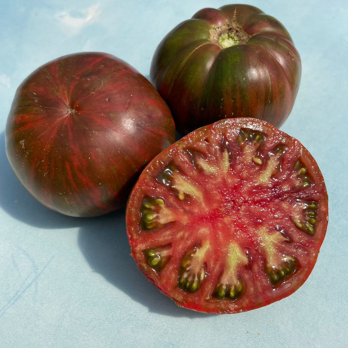 Pink tie-dye Berkeley tomato, fresh organic vegetable from vendor-unknown with vibrant pink and red marbled skin.
