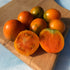 Apricot Zebra Tomato from Hudson Valley Seed Co., displaying vibrant orange and purple striped heirloom vegetables.