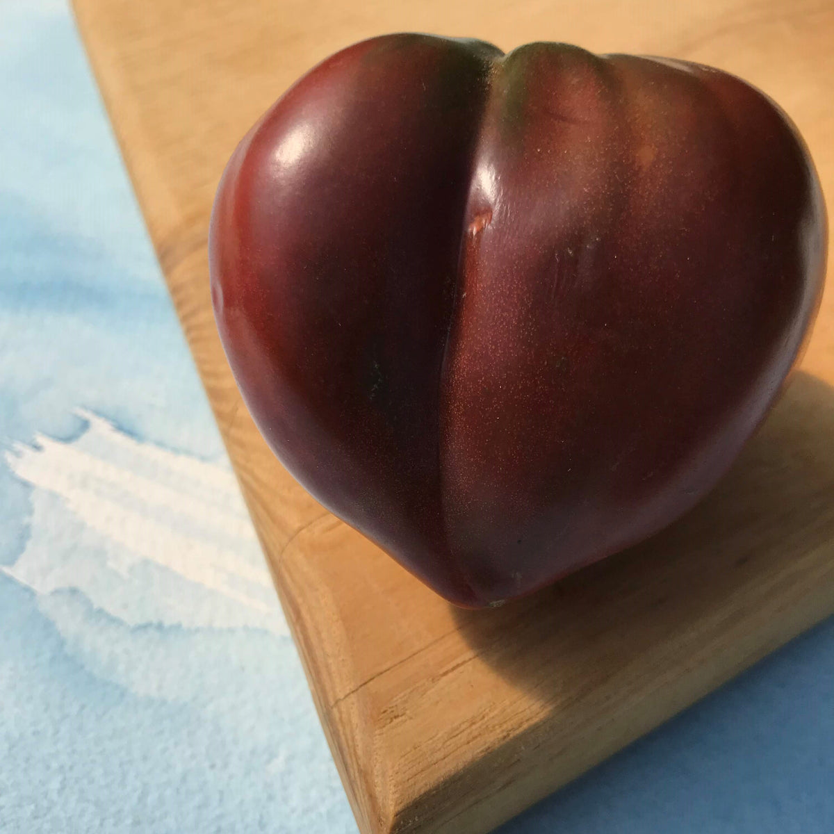 Purple Heart Tomato vegetable from Hudson Valley Seed Co., showcasing vibrant purple heart-shaped tomato on the vine.